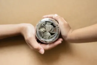 Hands holding coins in a jar