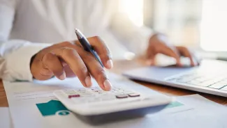 Hand on calculator and financial paperwork