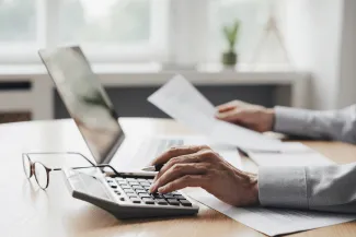 Lawyer at a computer with paperwork and a calculator