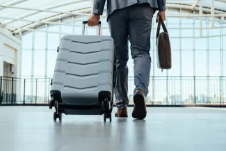 Foreign worker arriving in airport with suitcase and briefcase 