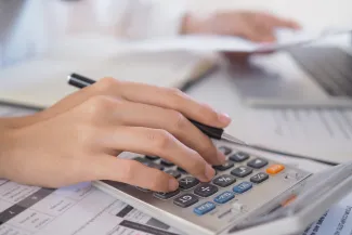 Woman's hand on calculator with paperwork