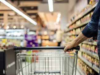 Shopping trolley in supermarket with hand on handle