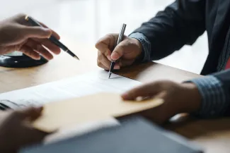 Hands holding pens over a document