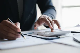 Man's hands working on calculator and paperwork