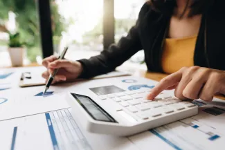 Woman working on calculator and paperwork