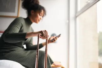 Woman using phone and holding suitcase