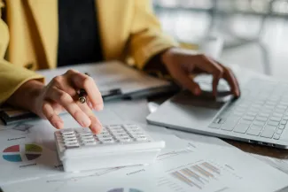 Woman working on calculator and paperwork