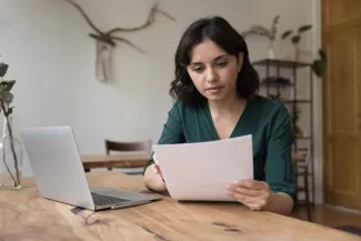 Serious women at laptop looking at document