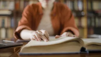 Woman holding pen looking at legal dictionary