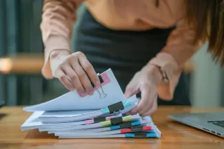 Standing woman sorting through pile of paperwork