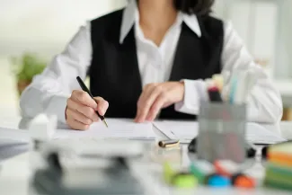 Woman at desk with pen in hand going over employment paperwork