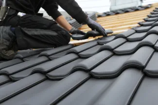Roofer adding tiles onto roof