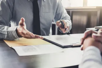 Two people talking over a desk about paperwork
