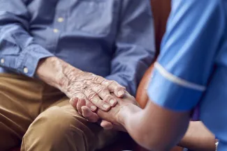 Care worker holding patient's hand