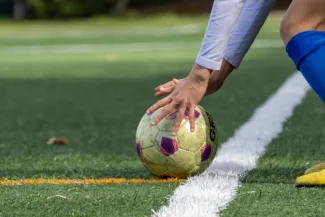 Woman placing football on pitch