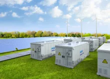 Battery energy storage system in field with solar panels and wind turbines