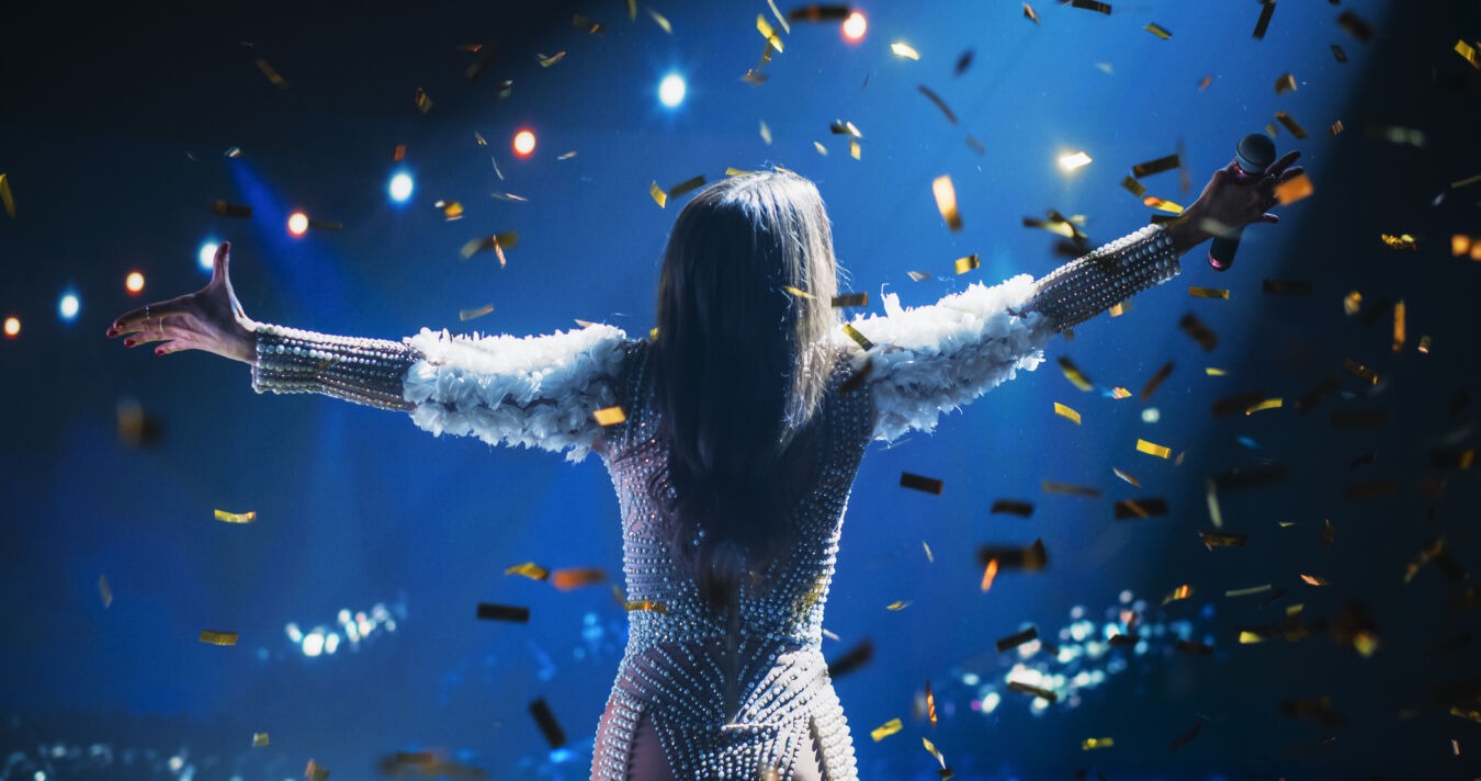 Pop star in front of crowd on stage with confetti raining down