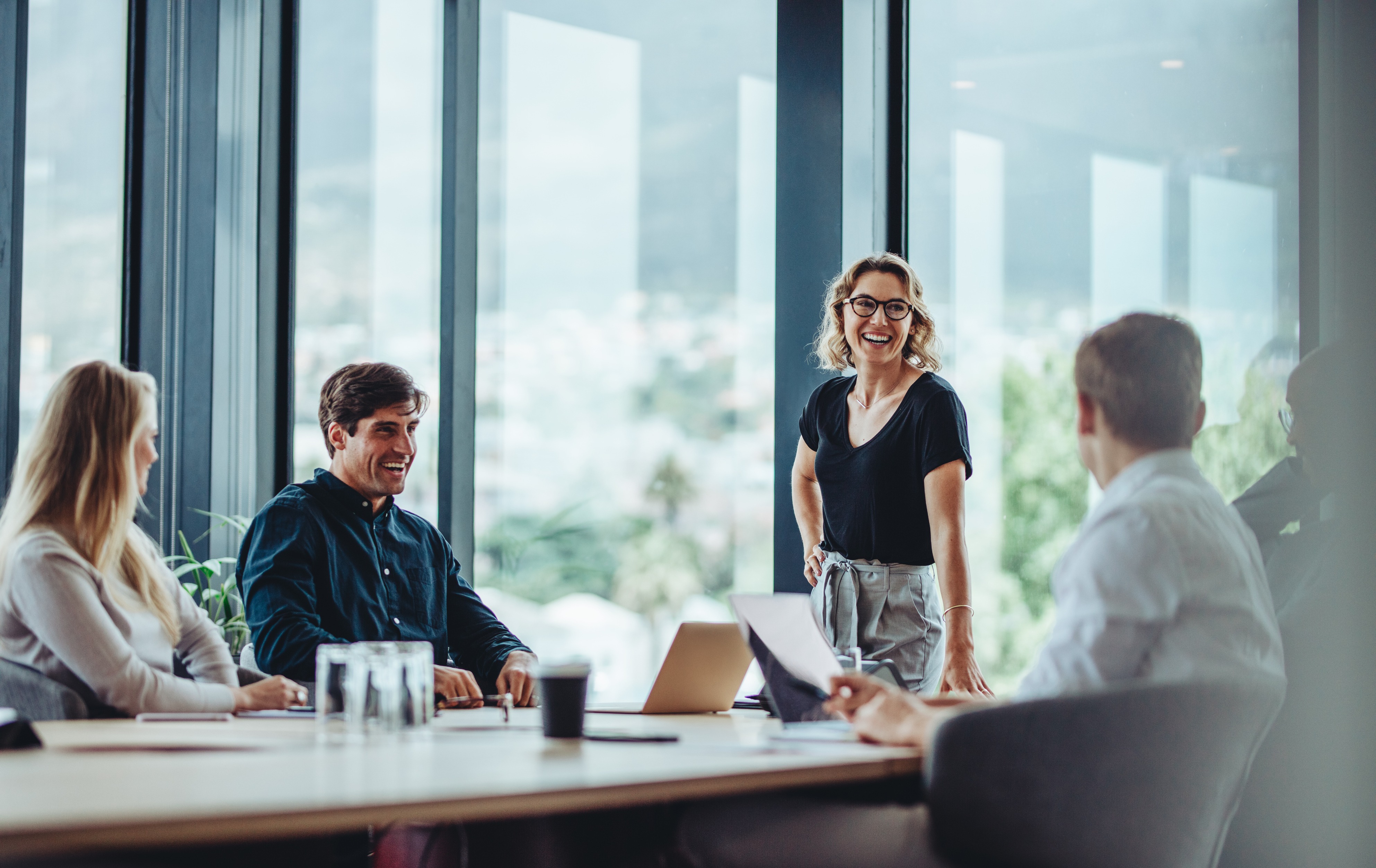 Boardroom meeting with lush greenery seen through windows in background