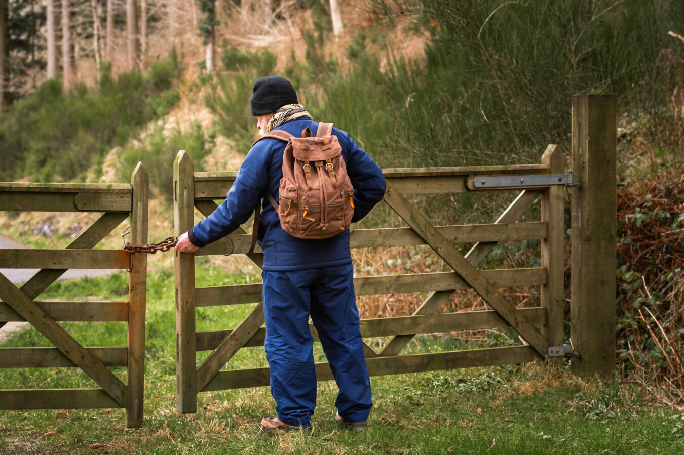 Older man standing at locked rural gate