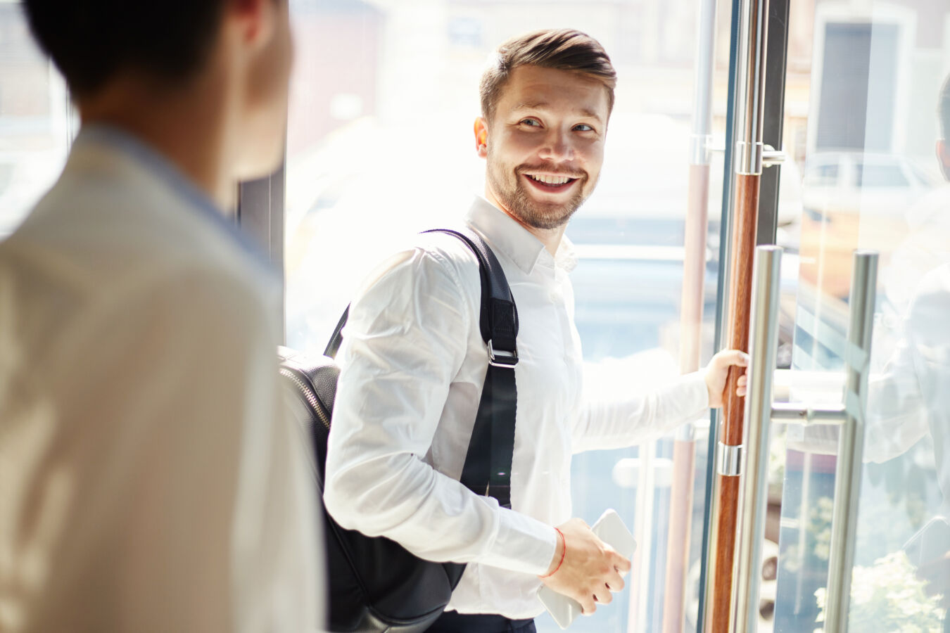 Man with hand on door exiting business building