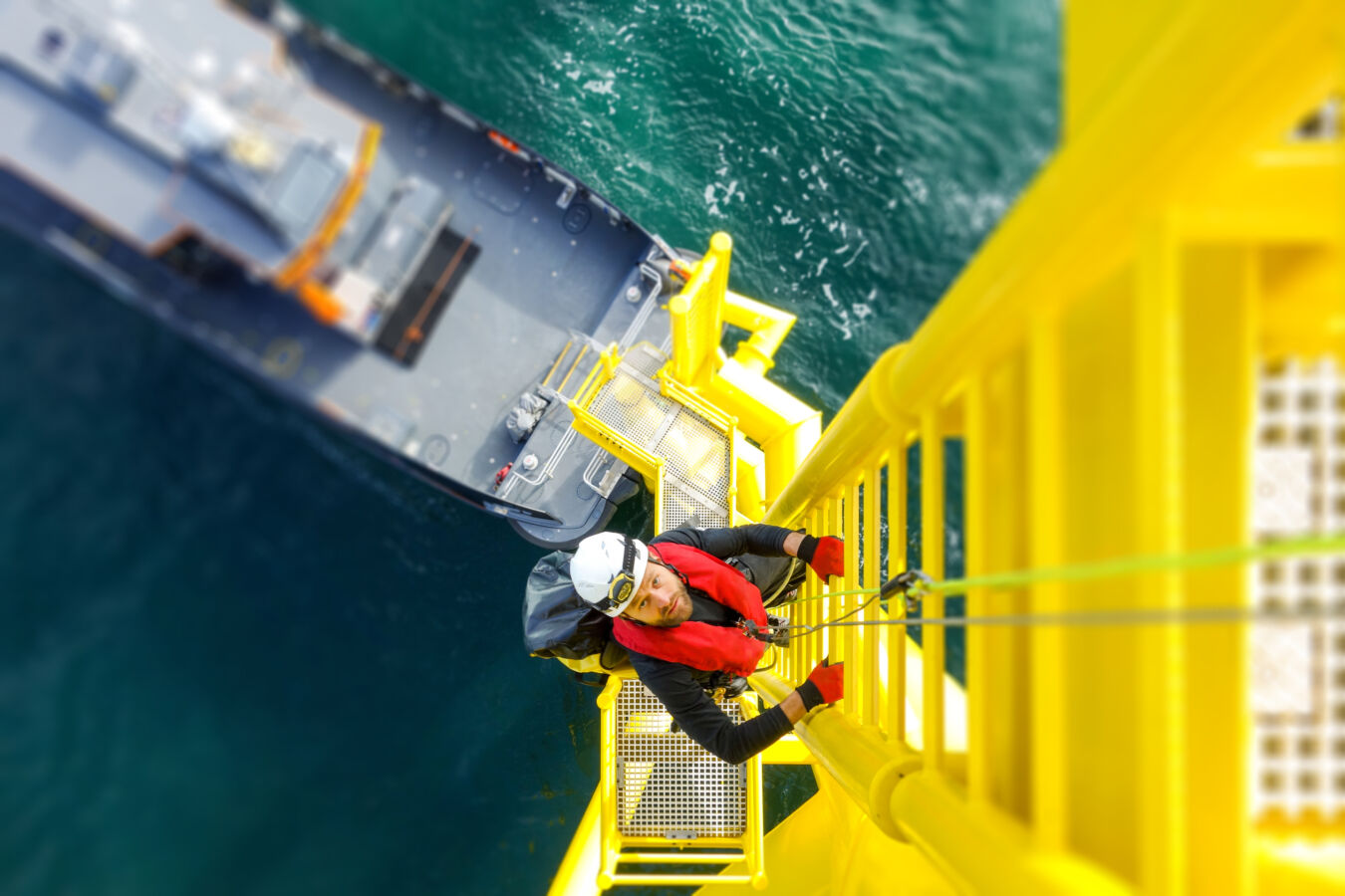 Worker climbing up a wind turbine ladder from a boat