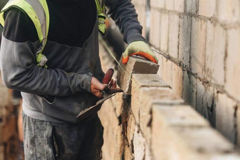 Building worker bricklaying wall