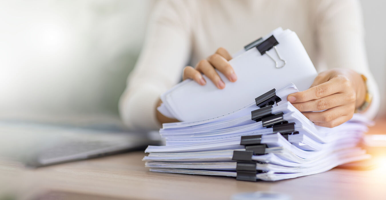 Woman pulling clipped paperwork from stack