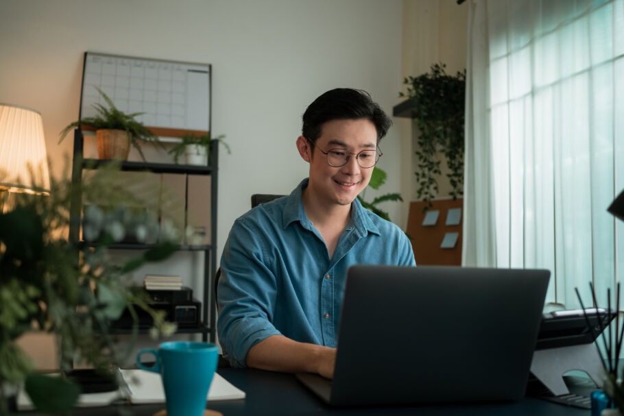young man working from home sitting at his laptop